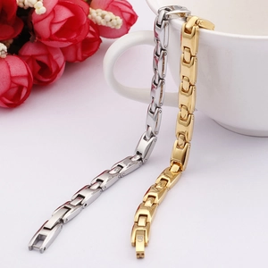 Detail of gold and silver titanium steel bracelets with germanium stones on a white cup