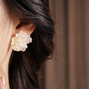 Gros plan de boucles d'oreilles fleur élégantes avec cristaux portées par une femme