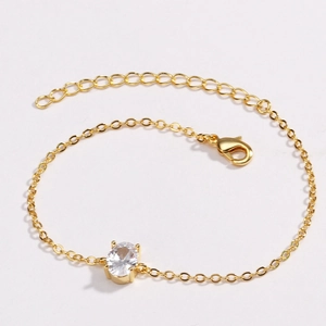 Detailed close-up of gold plated bracelet with emerald green oval zircon and lobster clasp
