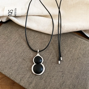 Detail of leather gourd pendant necklace with silver metal trim on textured book