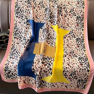 Detail of leopard print silk scarf with geometric color blocks on a leather sofa
