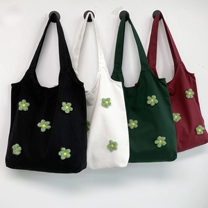 Detail of canvas tote bags in four colors featuring 3D knitted flower decorations