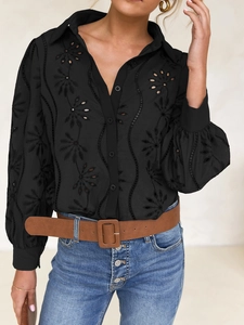 Detailed close-up of black hollow-out embroidery texture and button-front on women shirt