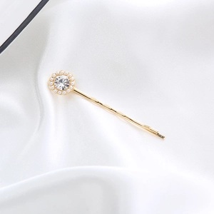 Detailed view of a gold hair clip with a large rhinestone surrounded by white pearls