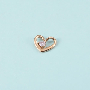 Détail d'un pendentif cœur en or rose avec une pierre de naissance rose sur fond bleu