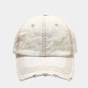 Close-up of distressed washed beige baseball cap featuring ripped edges and vintage canvas