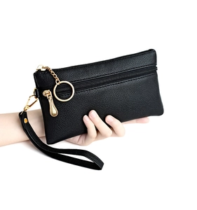 Detail of black textured leather clutch bag with golden metal zipper and wristlet strap