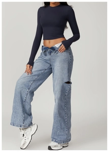Detail shot of light blue wide-leg jeans featuring a fold-over waist and distressed rip