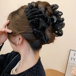 Detail of large black bow hair claw clip with rhinestones worn by a model in soft lighting