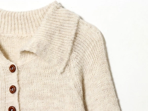 Detail of oatmeal polo neck knit cardigan featuring dark amber buttons and soft texture