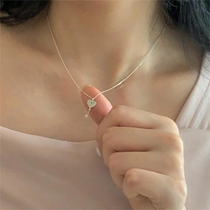 Detailed close-up of a sterling silver heart key pendant necklace worn by a model