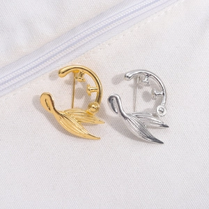 Detailansicht minimalistischer geometrischer Broschen in Gold und Silber in Fischform