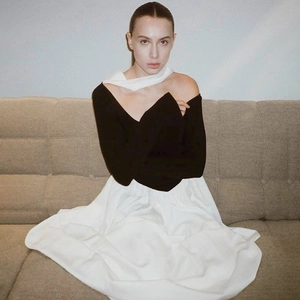 Detailed view of women's off-shoulder black top and white maxi skirt set in a modern indoor setting