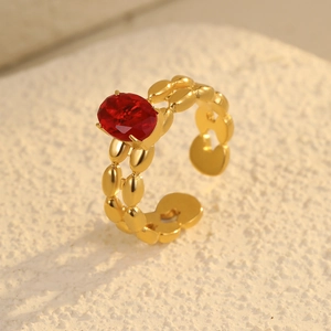 Vista macro di un anello a catena in acciaio placcato oro 18K con gemma ovale rossa lucida