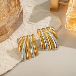 Détail macro de boucles d'oreilles géométriques bicolores à texture froissée or et argent