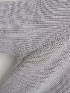 Detailed macro view of the grey knit cardigan showing high-quality stitching and rib texture