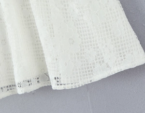 Gros plan sur le tissu en dentelle blanche avec des motifs floraux évidés complexes