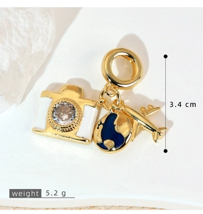 Detail of travel charms with gold airplane, globe and camera on white texture