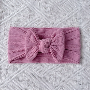 Close-up of pink nylon baby headband showing soft ribbed texture and large bow detail