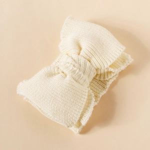 Close-up of a white knitted baby headband featuring a soft double-layer yarn bow design