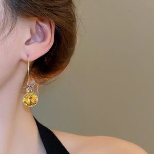Close-up of elegant hanging earring with vibrant yellow zircon and silver metal frame