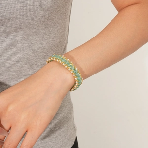 Close-up of woven pearl bracelet with green crystal beads on a model's wrist