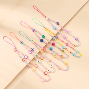 Close-up of colorful beaded phone straps with clay smiley faces and flower charms