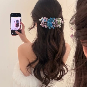 Romantic floral hair clip with blue and purple gypsophila flowers on wavy long hair
