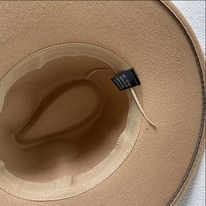 Détail de l'intérieur du chapeau en feutre camel montrant l'étiquette coton et polyester