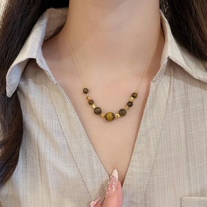 Detail of 18K gold plated necklace with brown tiger eye beads on a female model