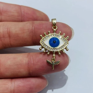 Detailansicht des goldenen Evil Eye Anhängers mit blauem Stein und kleinem Engel-Anhänger