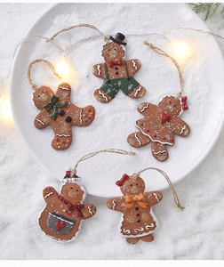 Detail of five festive gingerbread man ornaments with colorful scarves on a snowy background