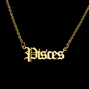 Macro shot of gold gothic Pisces zodiac letter pendant necklace on black background
