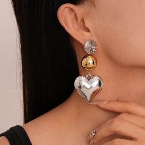 Exaggerated contrast metal geometric heart earrings worn by a model in a side view