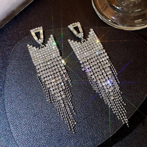 Macro shot of silver tassel earrings with sparkling rhinestones on dark leather background