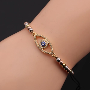 Detail of gold evil eye bracelet with white zircons and blue eye charm on a wrist