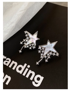 Detailed close-up of silver shooting star earrings with zircon and mother of pearl inlay