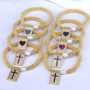 Detailed macro view of gold beaded bracelets with heart and cross zircon charms