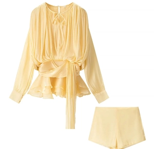 Detail of light yellow ruched long-sleeve top and matching shorts with tie neckline