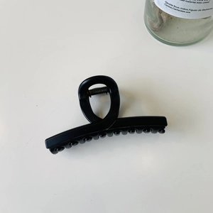 Vue de dessus d'une élégante pince à cheveux noire mate au design minimaliste français
