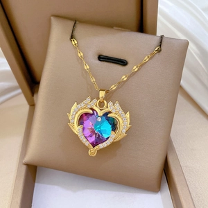 Close-up of golden heart necklace with gradient crystal and wings in a jewelry box