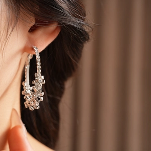 Vue macro de boucles d'oreilles créoles argentées avec paillettes et strass brillants