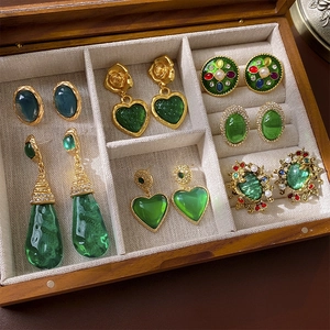 Vintage green heart earrings and retro golden jewelry displayed in a wooden box