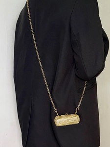 Detail of a luxury mini lipstick bag with golden rhinestones and a fine chain strap