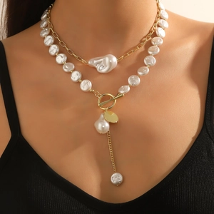 Close-up of double-layered baroque pearl necklace with gold OT buckle and tassel detail