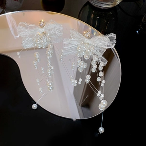 Detail of lace bow earrings with rhinestone center and hanging faux pearl tassels