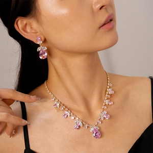 Parure de bijoux dorés avec collier et boucles d'oreilles cristaux roses sur modèle