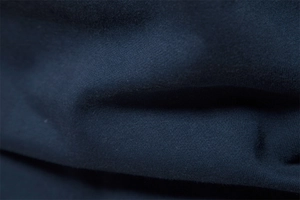 Macro shot showing high-quality dark blue knitted fabric texture and soft cotton blend grain