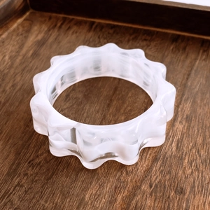 Vue détaillée du bracelet festonné en acrylique avec texture marbrée et bords ondulés