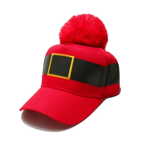 Detail of red Christmas baseball hat featuring a plush pom-pom and gold belt embroidery